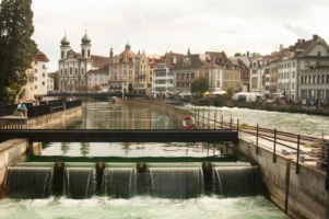 REUSS RIVER NEEDLE DAM, LUCERNE, SWITZERLAND Reuss River Needle Dam with Jesuit Church and Old Town architecture in Lucerne, Switzerland, photographed by Annamaria DiSanto